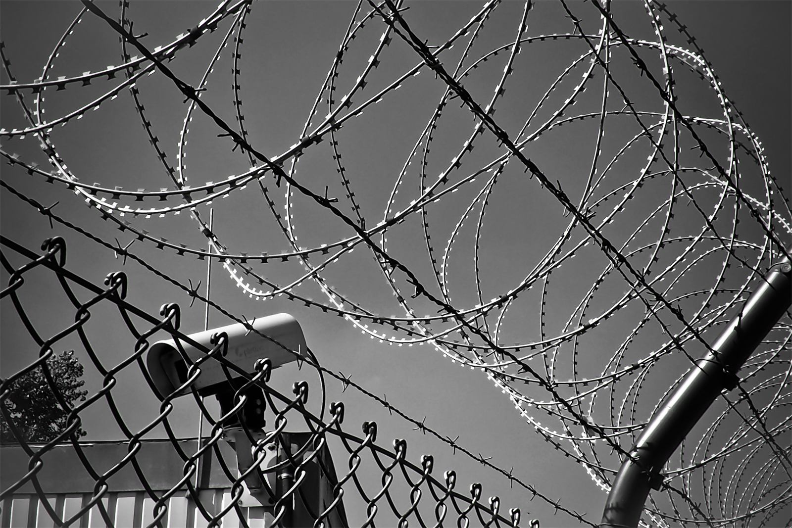 Überwachungskamera hinter Sicherheitszaun mit Stacheldraht